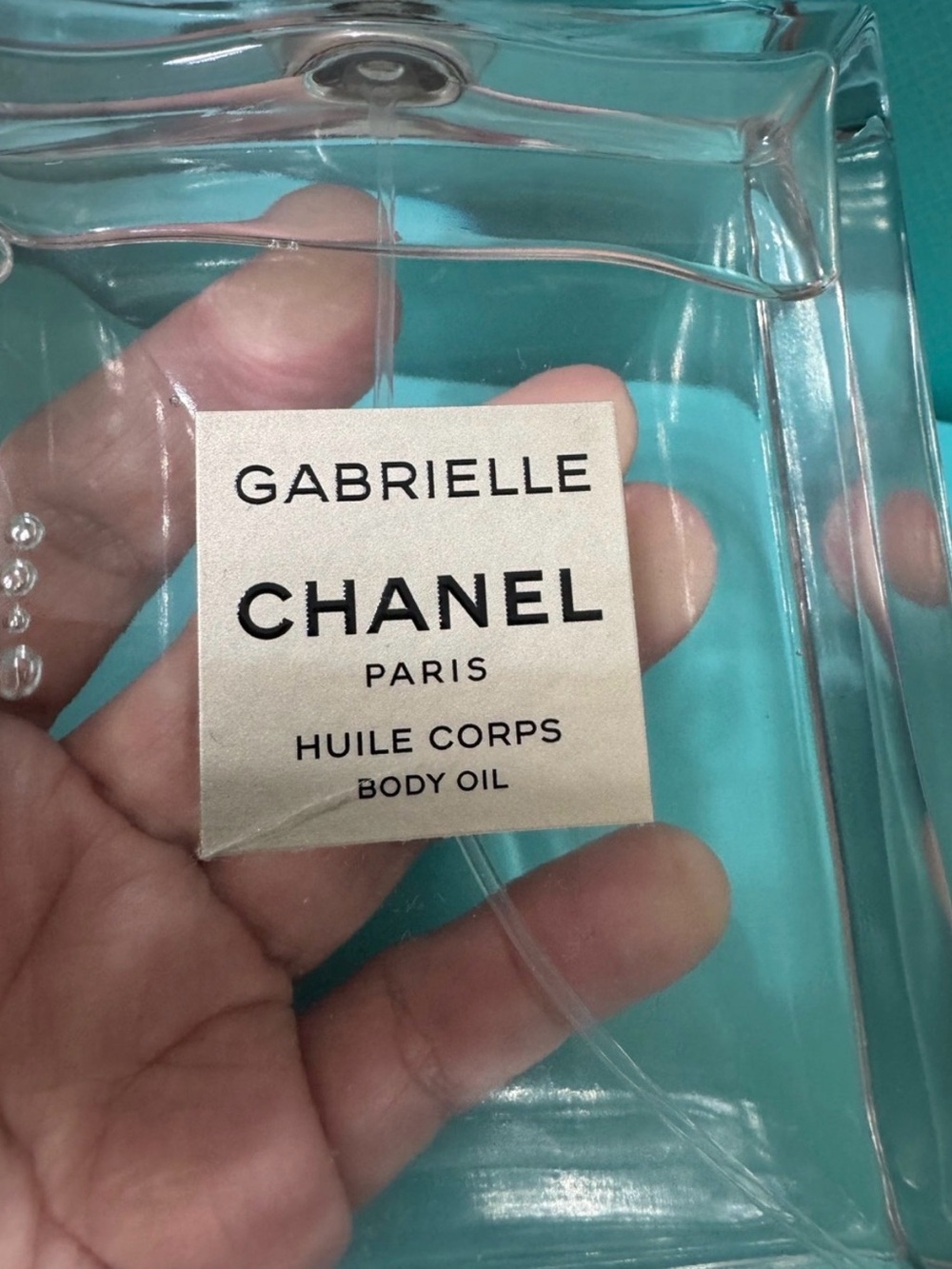 CHANEL Gabrielle Body Oil Clear Bottle with Aqua Backdrop